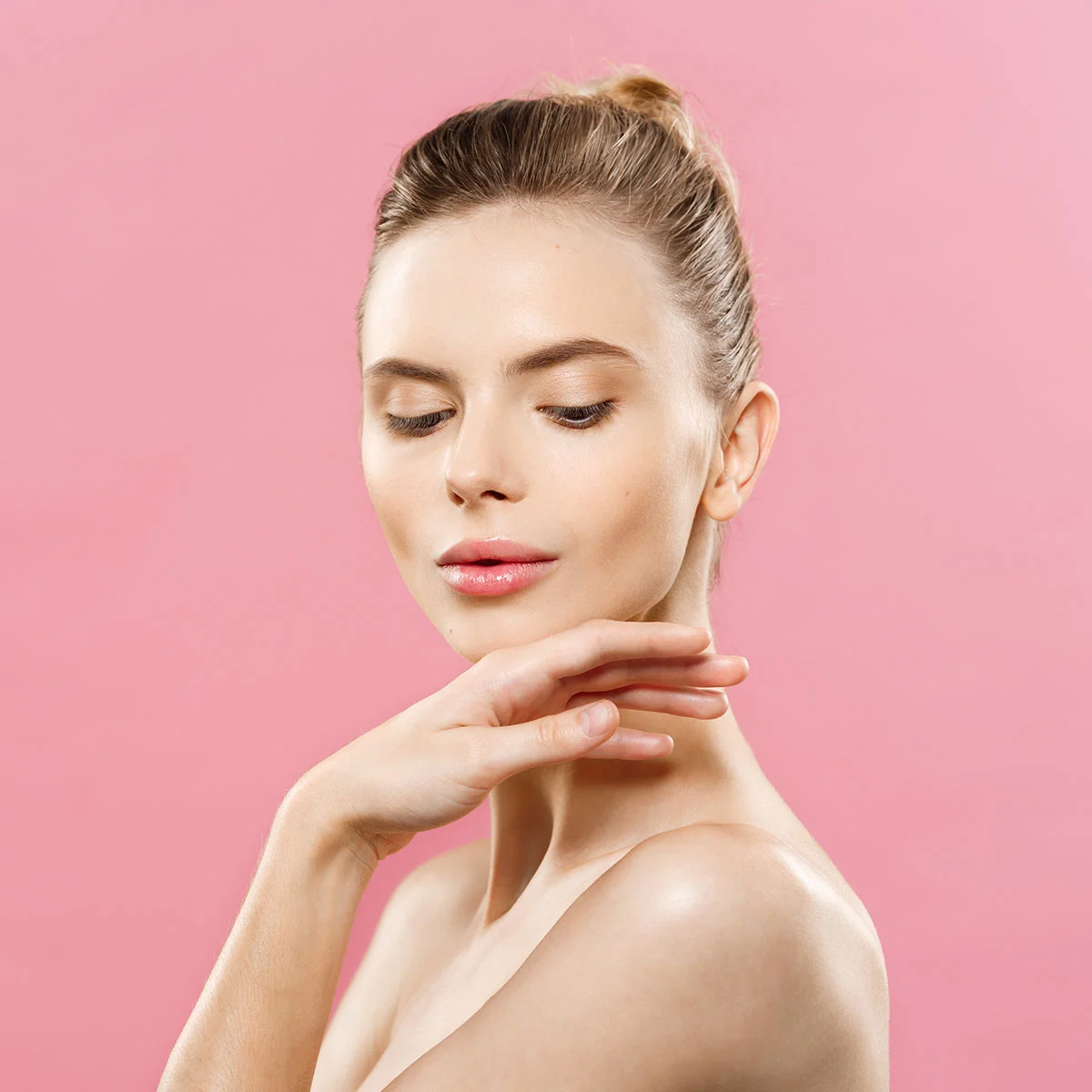 Portrait of a woman against a soft pink background showcasing smooth forehead skin from a Botox anti-wrinkle treatment.