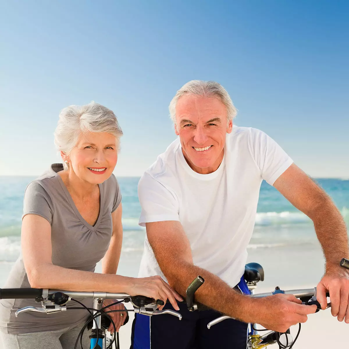 Smiling middle-aged couple standing closely outside, representing customized healthy aging and nutritional coaching plans.