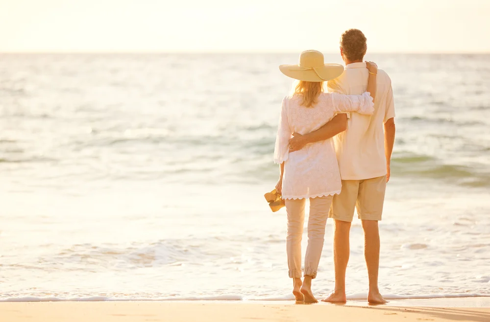 Senior couple walking happily along the beach, emphasizing restored intimacy and wellness after erectile dysfunction treatment.