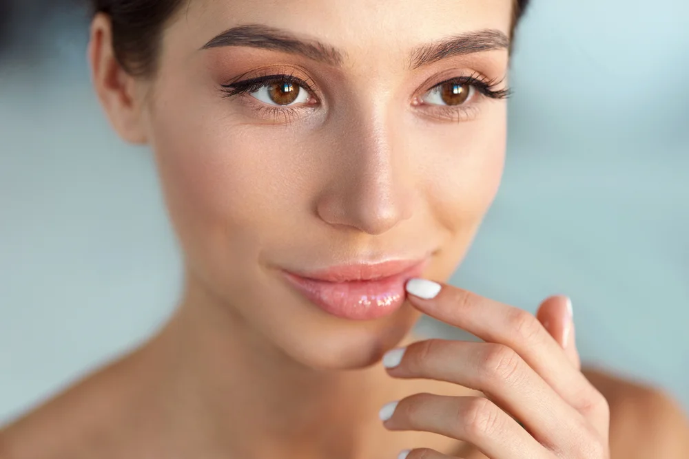 Close-up headshot of a woman with radiant skin and plump lips following a Juvéderm Volbella injectable treatment