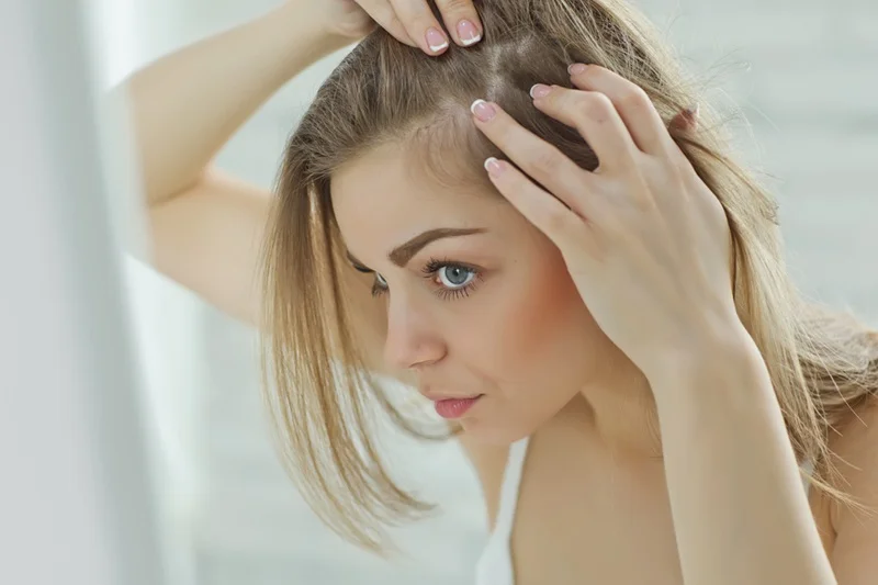 Close-up of a woman inspecting her scalp, representing hair restoration and follicle health from PRP therapy for hair loss.